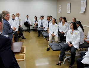 Professor discussing with a group of students in white coats